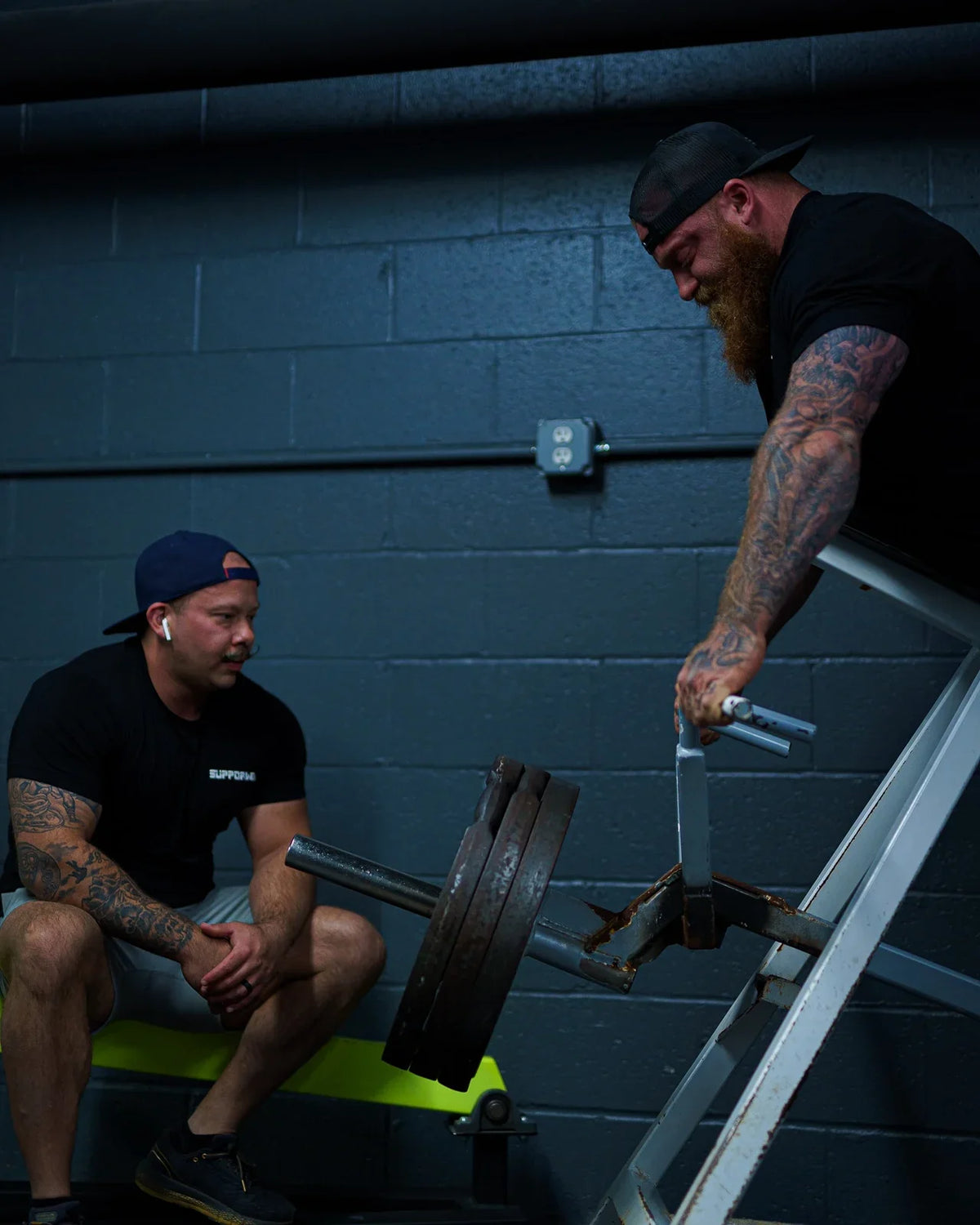 Athlete and training partner beside loaded gym equipment between sets