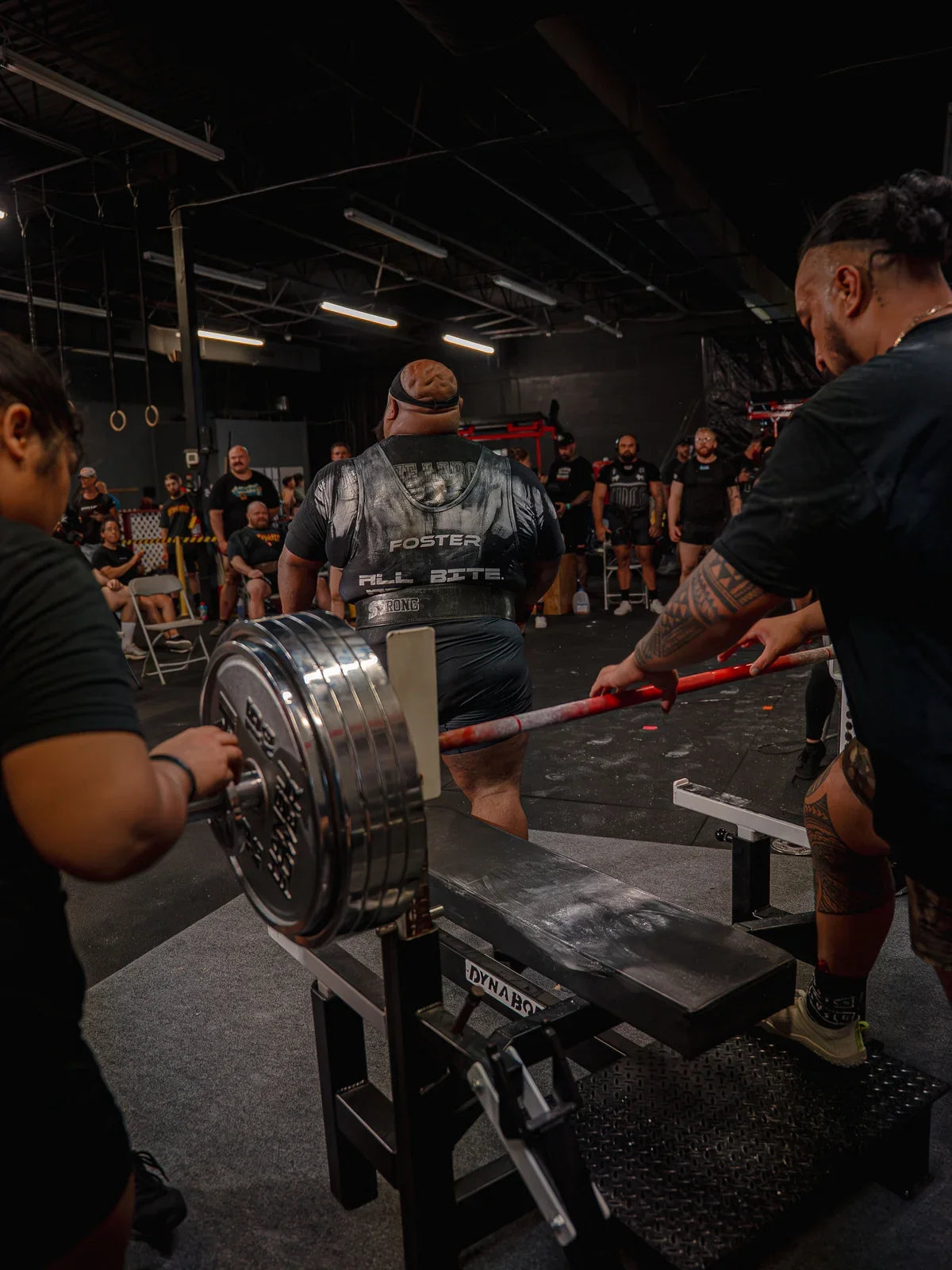 Powerlifting bench platform with a loaded barbell, athlete and spotters