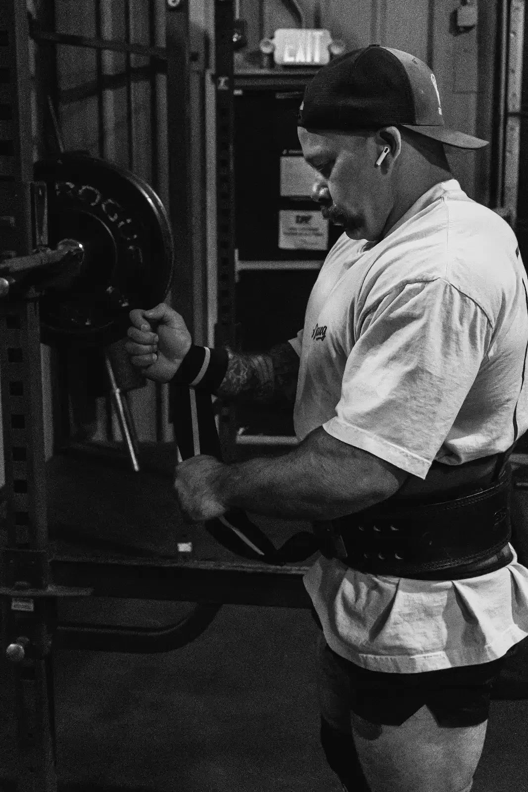 Athlete adjusting wrist wraps beside a loaded barbell