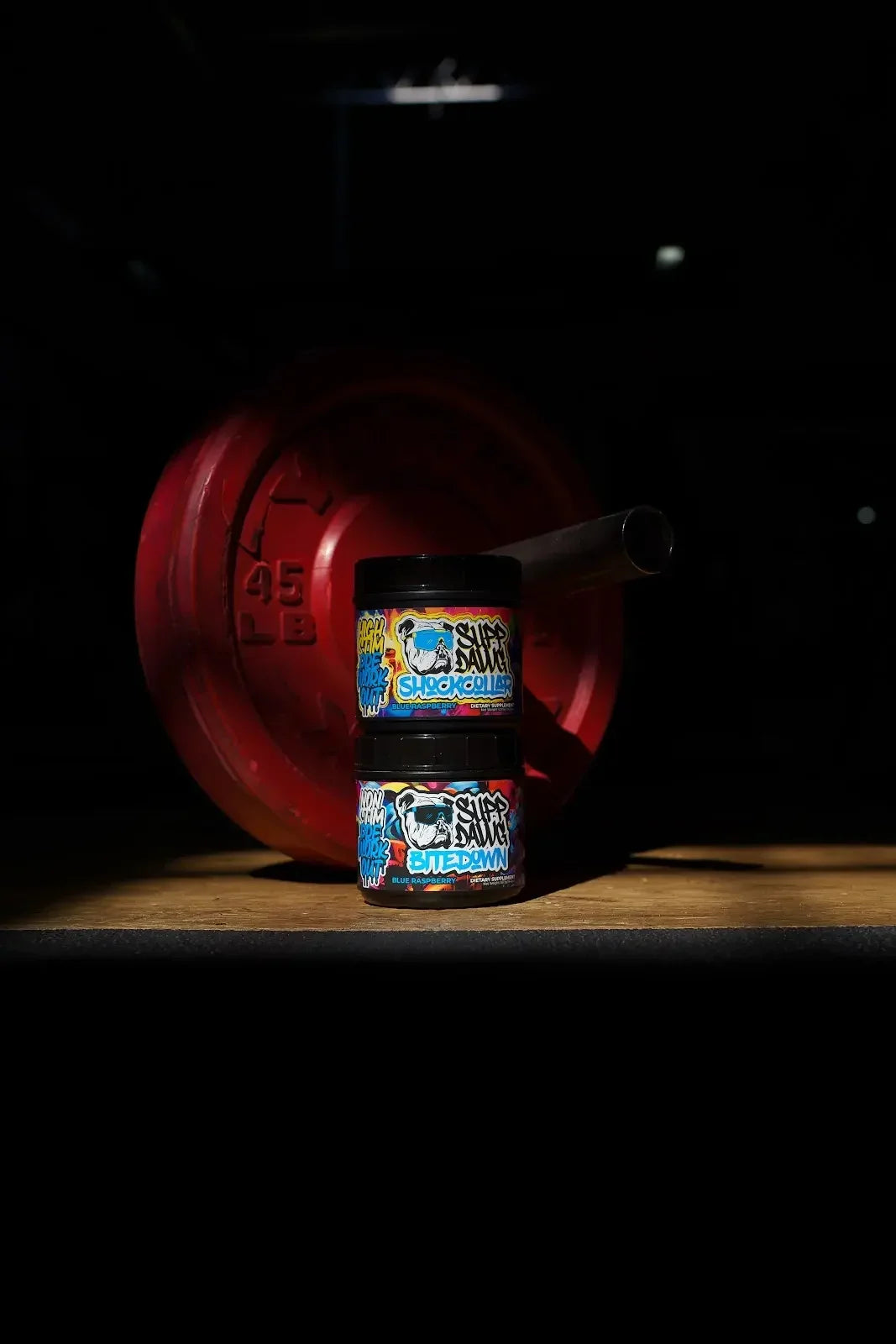 Shock Collar and Bite Down tubs beside a red weight plate