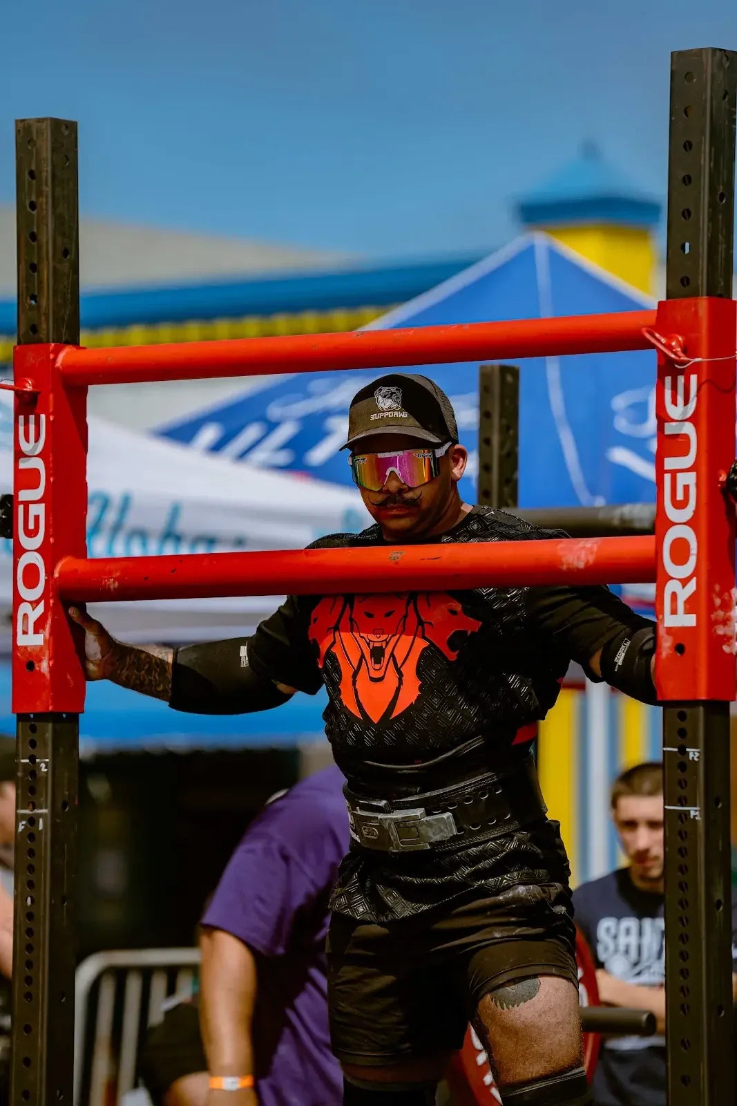Strongman athlete moving a red yoke at an outdoor competition
