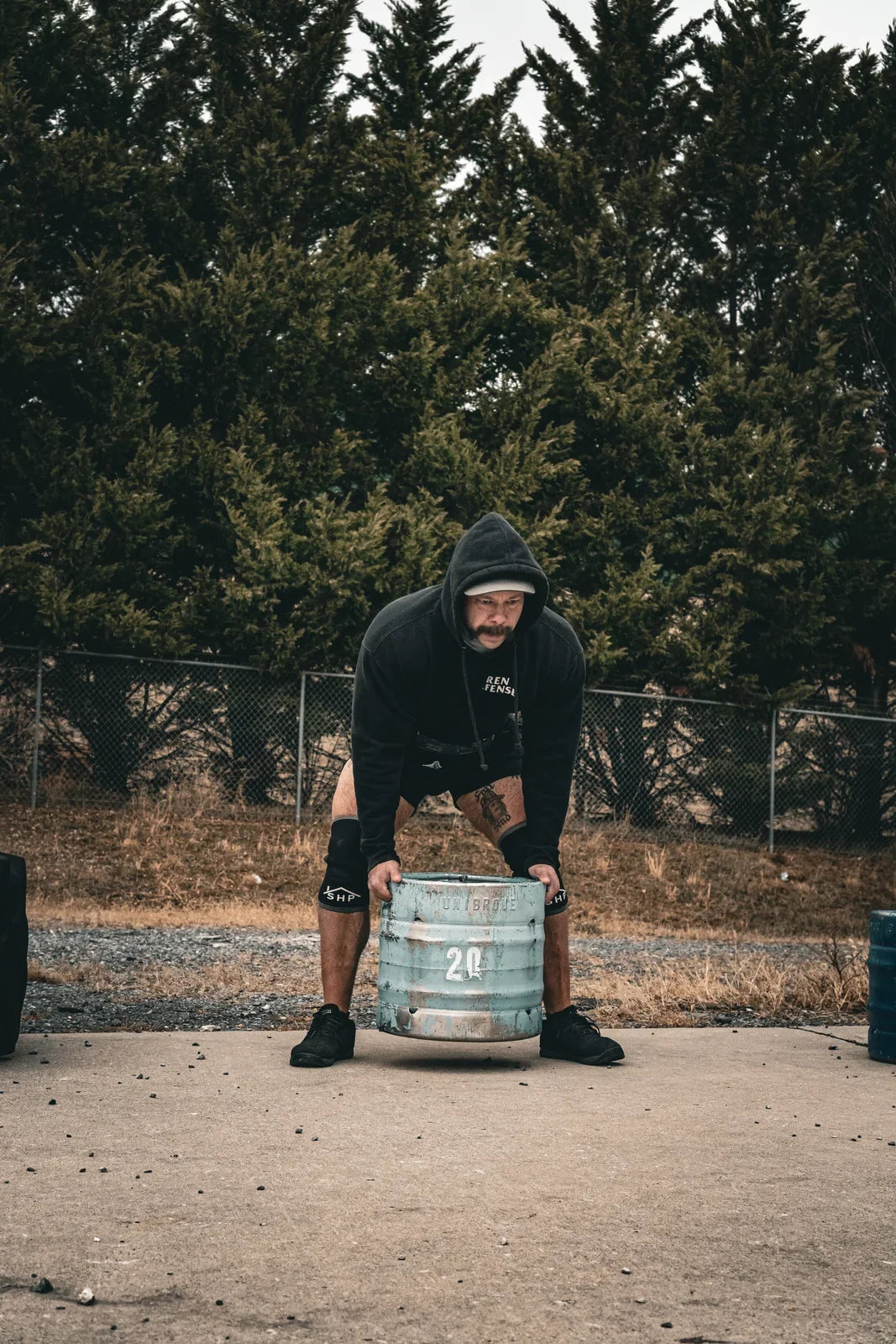 Strongman athlete preparing to lift a keg outdoors