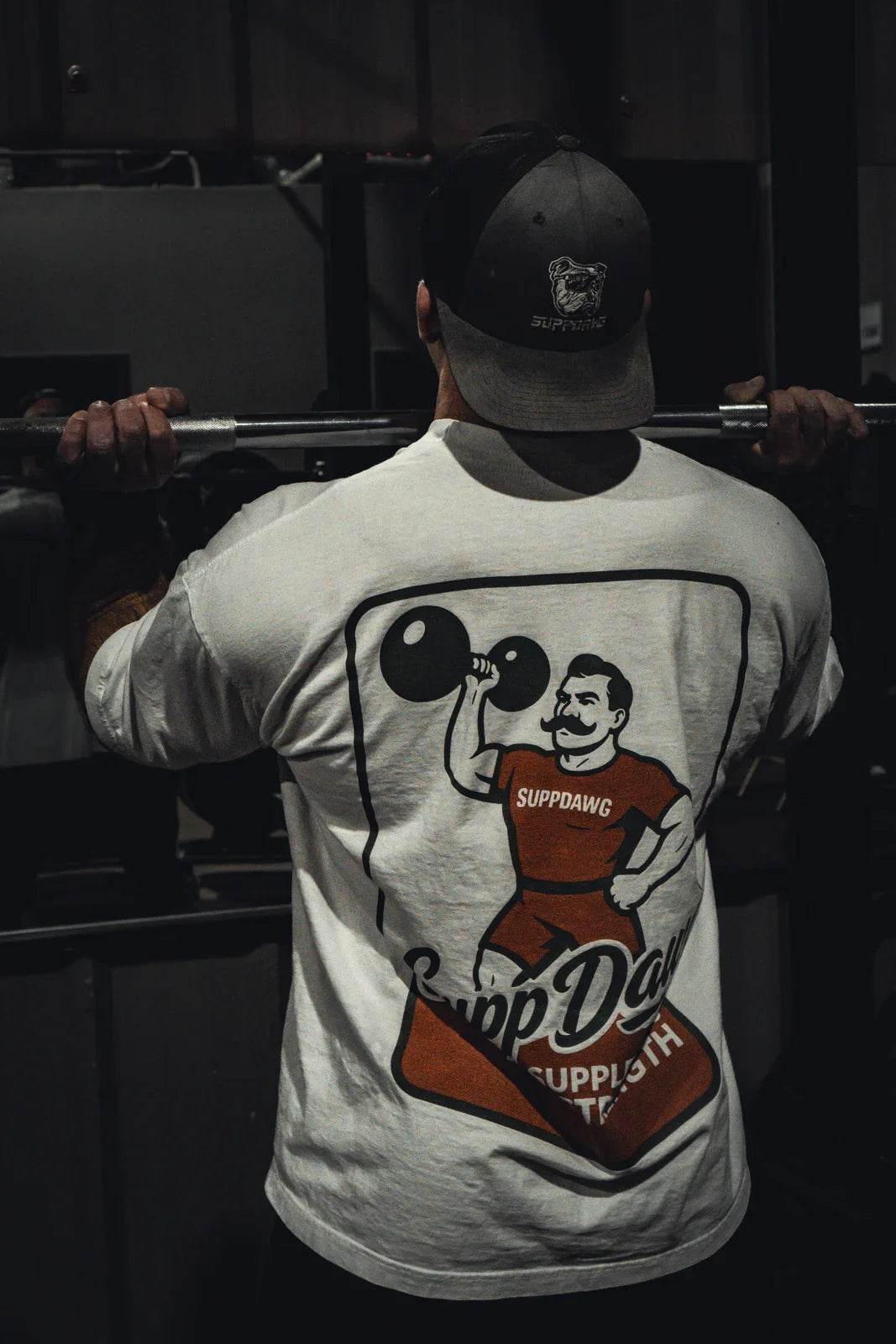 Athlete in a SuppDawg shirt preparing under a barbell