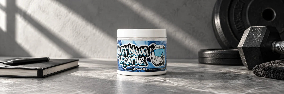 BuffDawg creatine tub beside a notebook and gym weights.