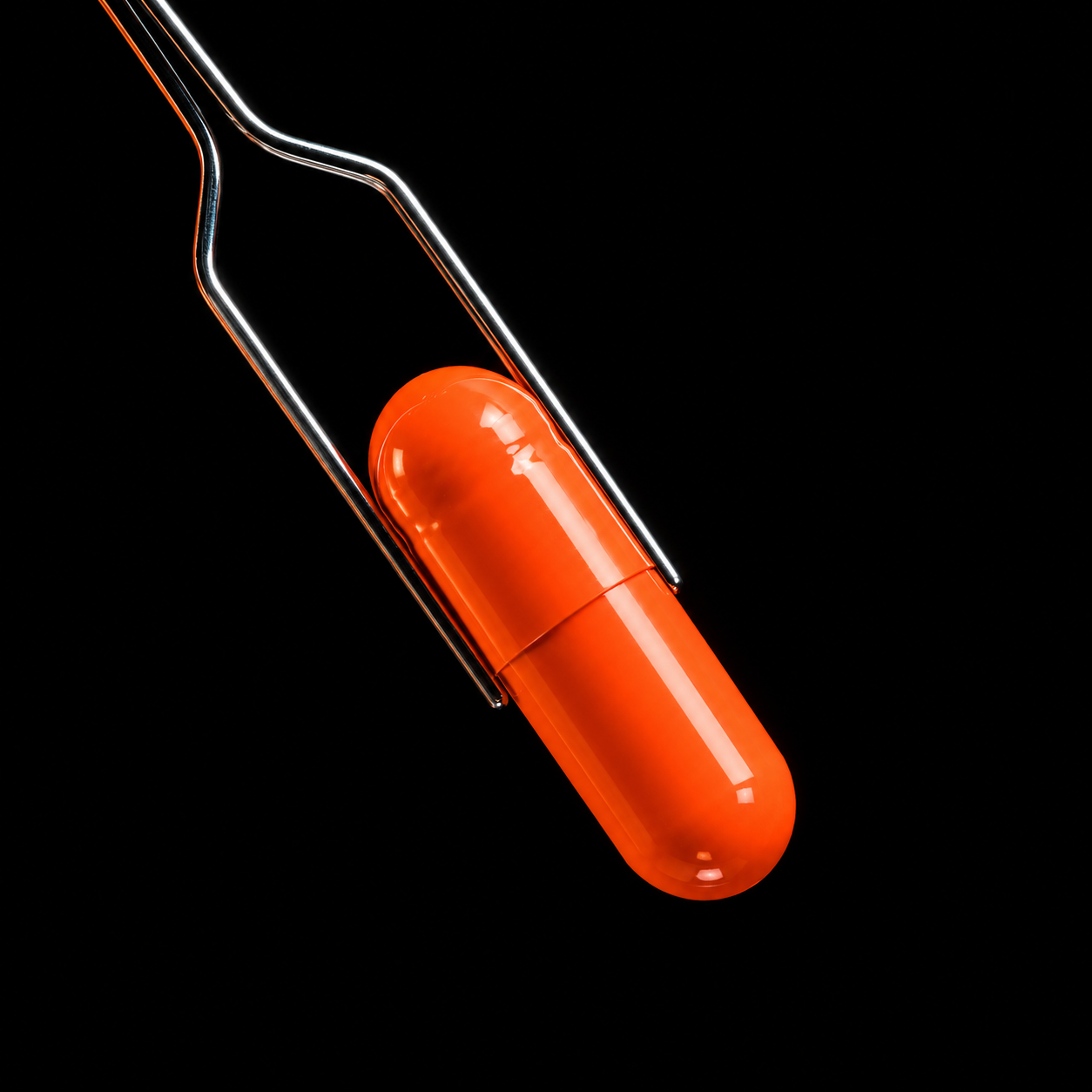 Orange HotDawg capsule held by tweezers